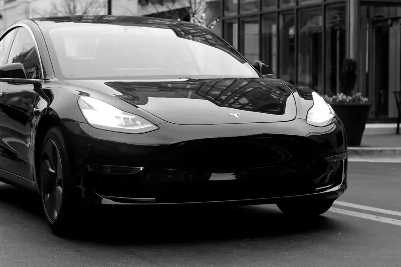 Tesla stationnée en ville avec câble de recharge, tapis de coffre et accessoires de rangement