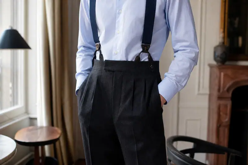Bretelles homme en toile tissée bleu marine fixées à un pantalon de laine sur une chemise claire
