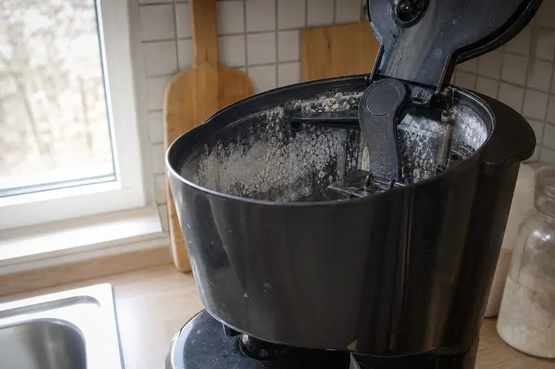 Cafetière filtre posée sur un plan de travail de cuisine, réservoir d’eau ouvert laissant voir des traces de calcaire