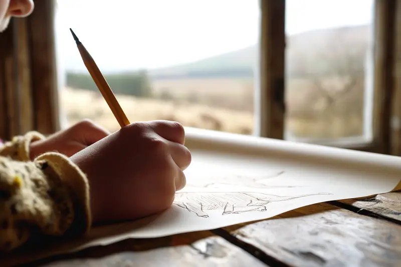 Main dessinant au crayon un mouton de profil construit avec des formes simples sur une feuille blanche