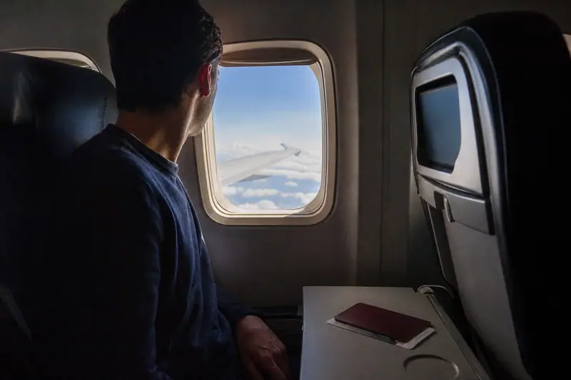 Voyageur assis près d’un hublot d’avion regardant la lumière du jour à l’extérieur