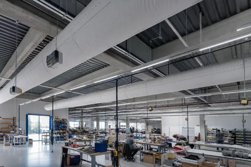 Gaine textile blanche en polyester suspendue dans un vaste atelier ventilé