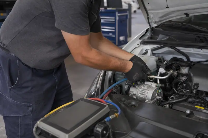 Technicien contrôlant les raccords d’un compresseur de climatisation dans un compartiment moteur