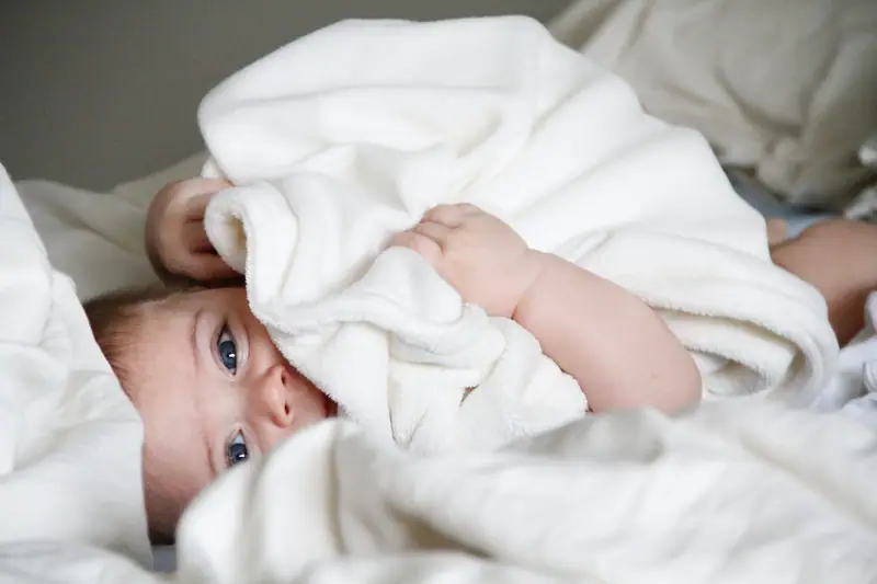 Parent dosant une lessive sans parfum avant de laver des vêtements de bébé en coton