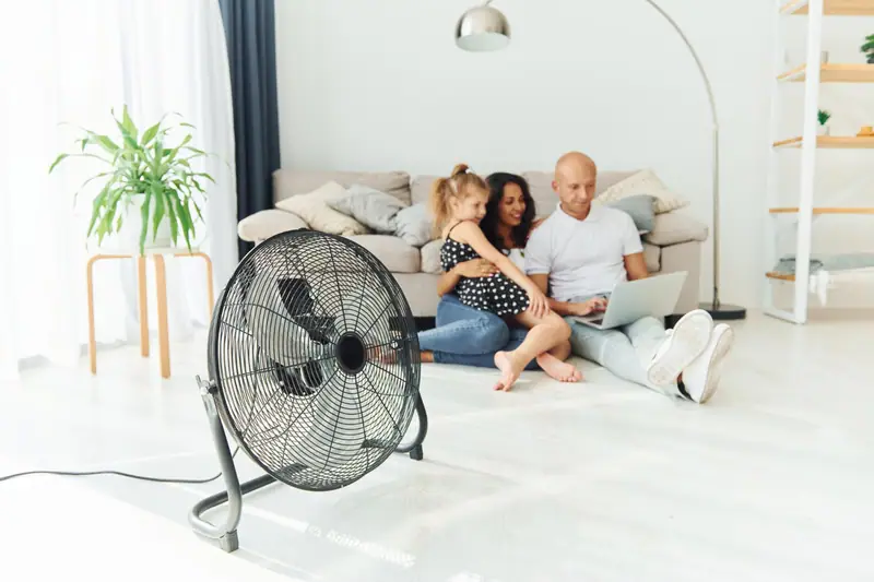 Store extérieur protégeant une baie vitrée tandis qu’un climatiseur mobile rafraîchit un salon