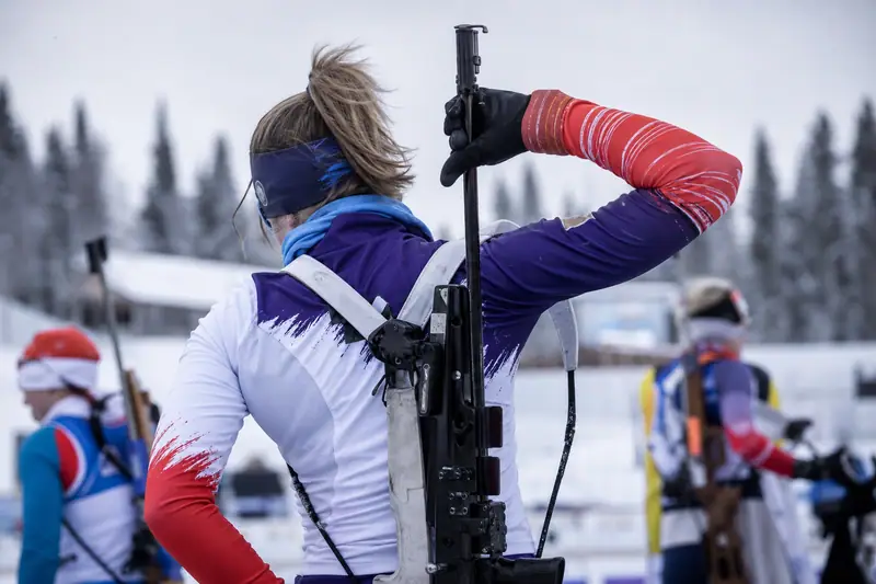 Biathlète en tenue technique ajustée sur une piste enneigée avant une séance de tir