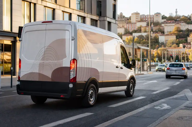 Utilitaire professionnel marqué circulant dans une rue urbaine de Lyon en fin de journée