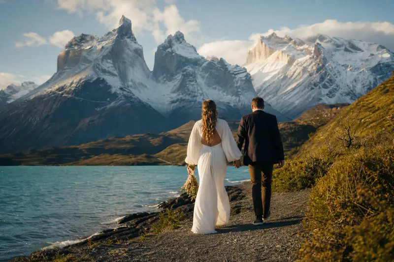 Couple marchant main dans la main devant un lac turquoise et les sommets de Patagonie