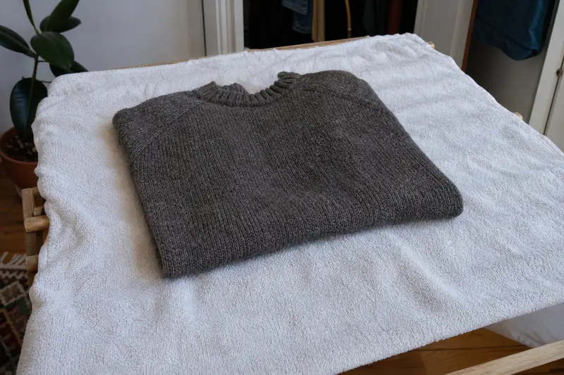 Pull en laine posé à plat sur une serviette pour sécher, plié soigneusement