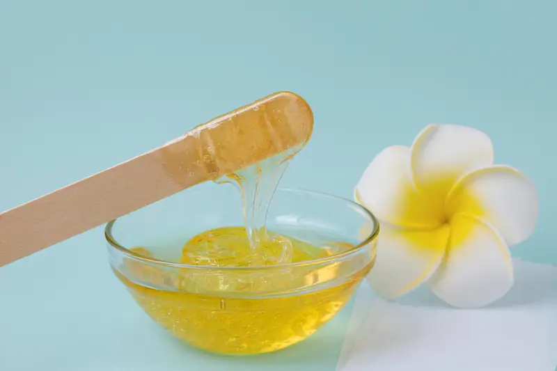 Artisane comparant des sacs de cire végétale et fiches techniques dans un atelier de bougies