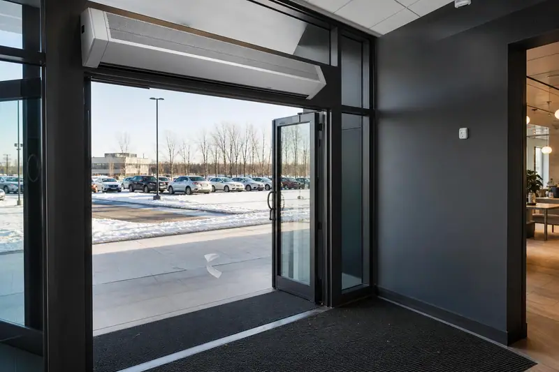Rideau d’air chaud installé au-dessus d’une porte d’entrée ouverte dans un hall lumineux