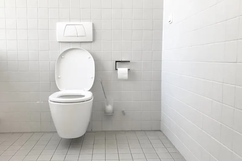 Bricoleur remplaçant le mécanisme de chasse dans un réservoir de WC ouvert
