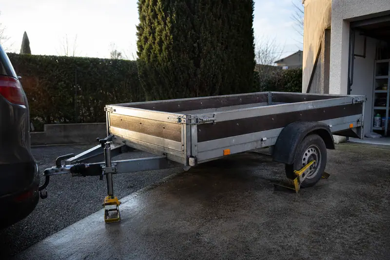 Remorque dételée sécurisée par un antivol de tête et un sabot de roue sur un sol pavé