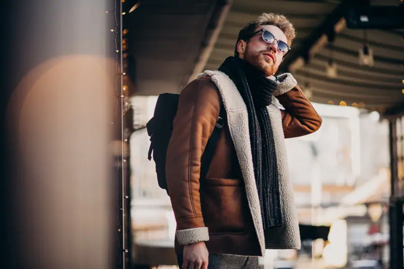 Homme de dos portant une veste bleu marine bien ajustée dans une rue urbaine lumineuse