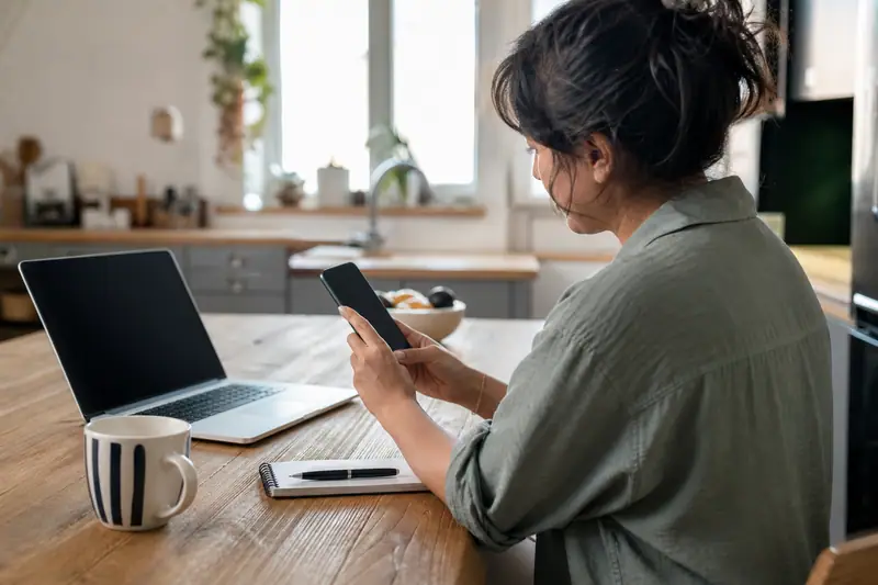 Personne consultant son application bancaire sur smartphone à une table, écran affichant une opération en attente