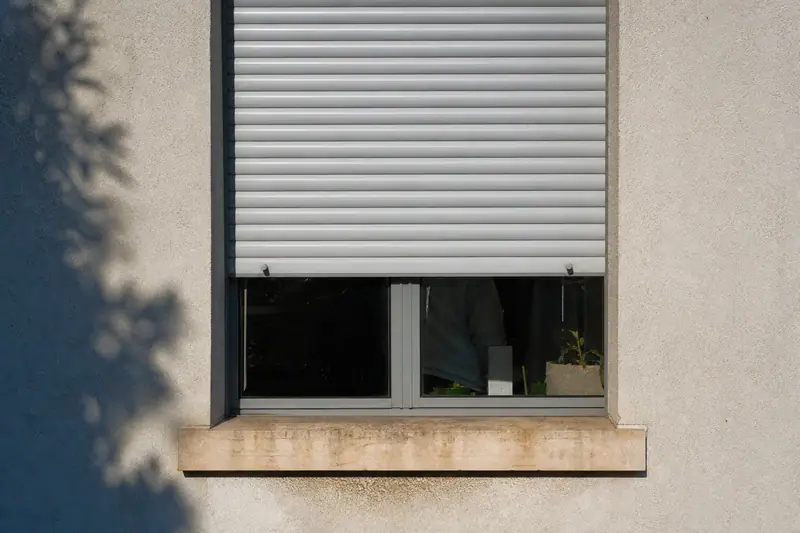 Volet roulant électrique partiellement fermé sur une fenêtre de façade